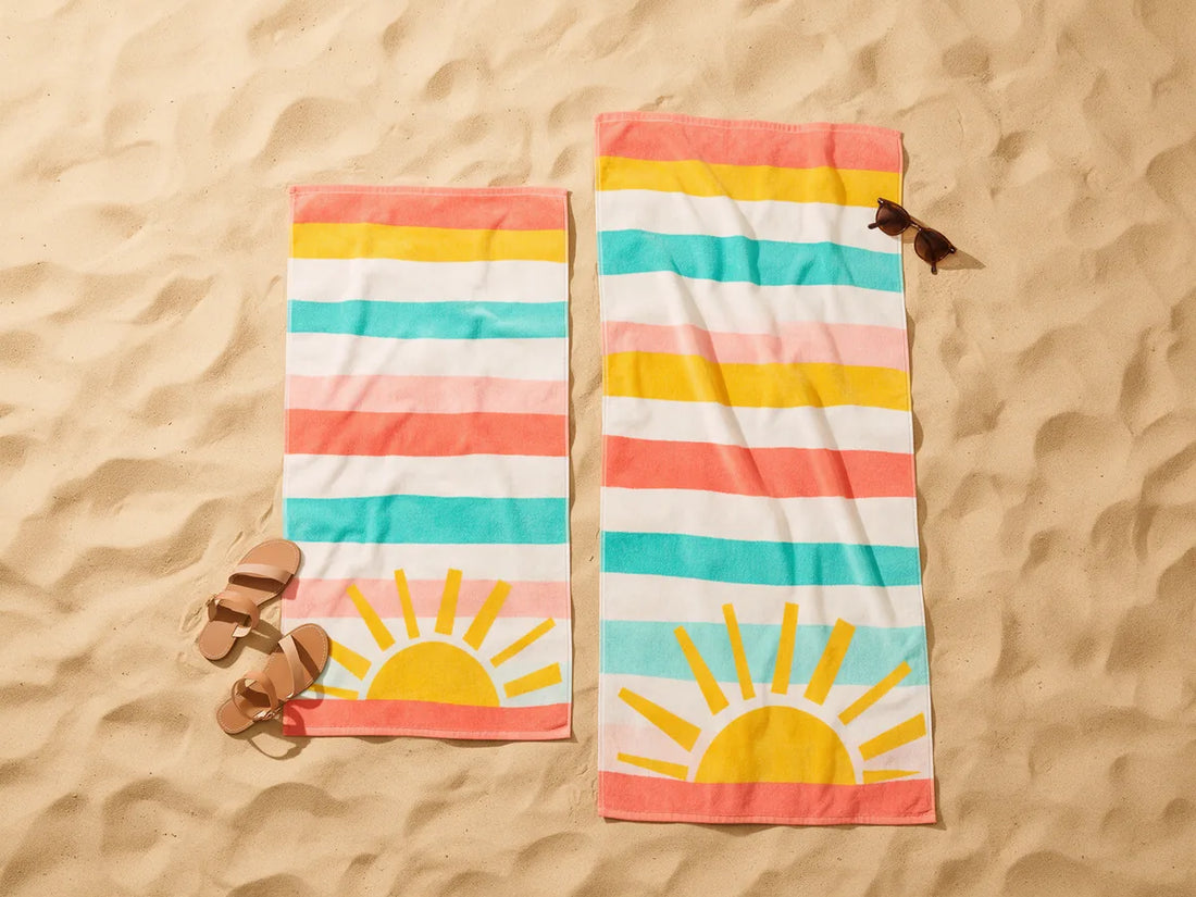 Two printed beach towels in different sizes laid side by side on the sand
